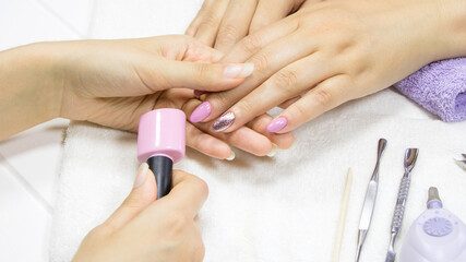 Obraz na płótnie Canvas The manicurist shows the client the color of nail Polish. The woman chooses the color of the gel Polish. Pink manicure, Nude, glitter, silver. Colorful, nail art. Manicure process in a beauty salon
