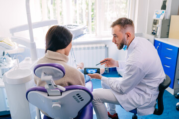 Obraz premium dentistry and healthcare concept. dentist with phone showing tee