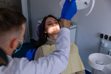 dentist working at dentist office, adjusting dental lamp, examin