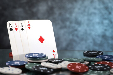 A pair of aces, hearts and diamonds, on a deck of playing cards. Poker playing chips on a dark and light blue background. Online gambling. Addiction. Falling playing cards and poker chips