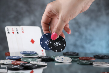 Close up of a woman hand holding poker playing chips with playing cards in a back. Online gambling. Addiction. Falling playing cards and poker chips
