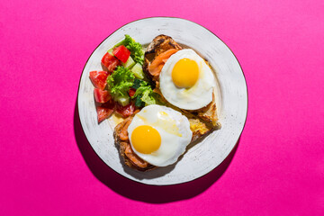 Fried eggs from two eggs on a pink background