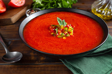 Close up of a plate with summer refreshing tomatoe soup gazpacho on dark rustic background