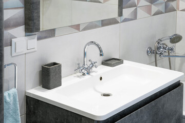 Modern bathroom interior with metal faucet and ceramic white sink. Bath accessories and mirror.