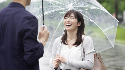 雨の日に傘を差してデートするカップル