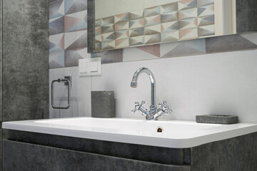 Modern bathroom interior with metal faucet and ceramic white sink. Bath accessories and mirror.