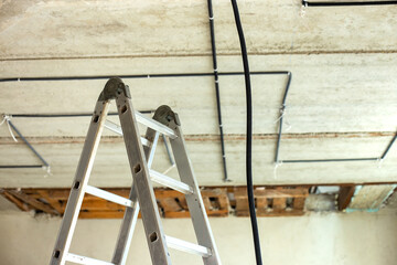 Aluminium ladder and electrical cables laid in protective corrugation installed on the ceiling and...
