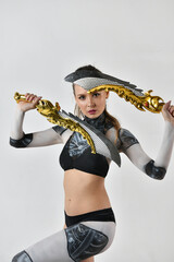 beautiful girl in a robot suit makes fighting movements with golden swords on a white background