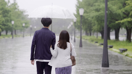 雨の日に傘を差してデートするカップル
