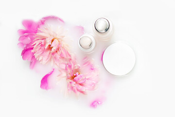 Fototapeta na wymiar Creams and peony flowers in a bath with milk. Conceptual photo: the best cosmetic tool for body and face care. Natural cosmetic.