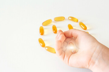 Kid's hand holds gelatin softgels Capsules of Omega-3 fats on white background. Eicosapentaenoic acid and fish oil. Organic dietary supplements concept