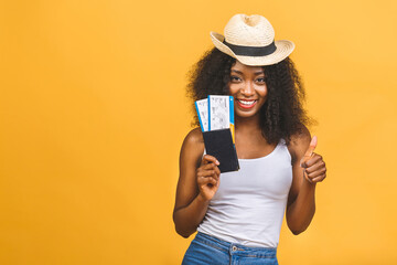 Travel, tourism and vacation concept - happy young african american black woman with air tickets isolated over yellow background.
