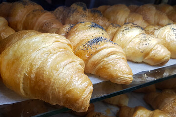 Close up freshly baked pastry croissants goods on display in bakery shop. Selective focus