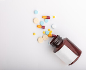 The medicine bottle fell and the pill was strewn on a white background.