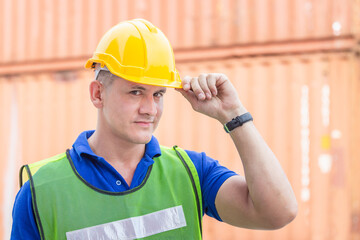 Cheerful factory worker man in hard hat looking at camera with joy, Happiness engineer at cargo containers concept