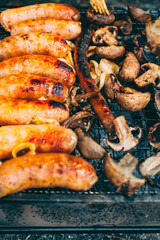 Cooking sausages with onions, mushrooms on the grill. Cooking on charcoal. Food on the nature. Lunch at the campsite. Picnic. Photo is close.