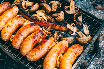 Cooking sausages with onions, mushrooms on the grill. Cooking on charcoal. Food on the nature. Lunch at the campsite. Picnic. Photo is close.