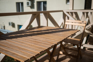 Wooden table with chairs stands on the balcony of the motel. Wooden table at a motel in sunny weather close-up.