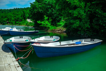 Several rowing boats on the shore of a beautiful lake. Rowing boats in turquoise water on a background of a forest in sunny weather.