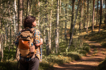 camping in the woods. girl in a hat with a backpack walks through the woods.