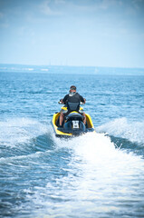 Fototapeta na wymiar Man of jet ski rider performs on the waves with much splashes goes to sea