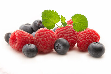 Fresh blueberries and raspberries with lemon balm leaf isolated