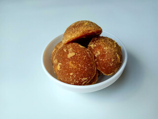 Gula jawa or javanese sugar or red sugar or palm sugar, in half ball shape, inside white bowl. Isolated in white background