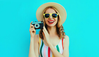 Summer portrait happy smiling young woman with retro camera wearing a summer straw hat on blue...
