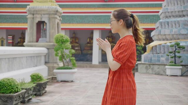 Side view of asian woman bowing and doing Asian greeting at buddhist temple in Asia, Thai greetings, pay respect