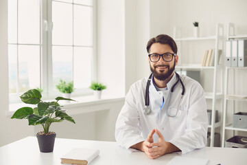 Smiling doctor communicating with patient online from his office. Specialist conducting web consultation with client