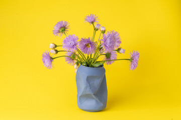bright summer bouquet of purple field daisies in an old blue jar on a yellow background