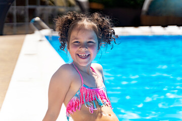 little curly-haired girl laughing by the pool