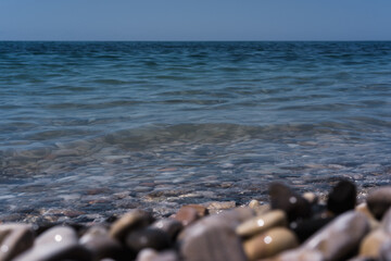 A wave rolls over the rocky shore. Pebble beach. Seashore.