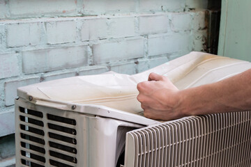 Image of angry man and broken item. .Male fist beats on the old air conditioner that crush from a strong blow. Concept of a person dissatisfied with a product or service.