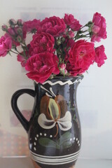 

A bouquet of small roses stands in a ceramic vase. The flowers are delicate and smell pleasant