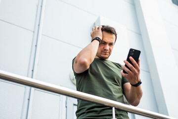 Confused man complaining after mistake checking phone content in the street