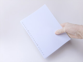 A hand with white latex glove holds some blank white papers. Isolated on a white background, side view.