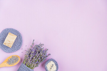 Lavender flowers are arranged on a purple background. cosmetic set with lavender herbs, handmade soap bars and sea salt. Flat lay, copy space