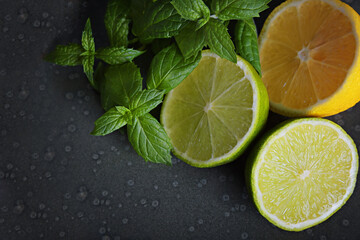 Lime, lemon and mint leaves lie on a plate on the gray background.
