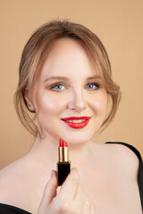 Girl holds red lipstick and smiles