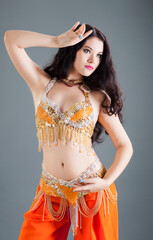 closeup young woman with long dark hair in belly dancer costume poses for photo