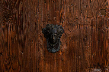 Door knocker in the form of a head on a wooden door