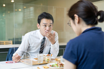 アクリルパーティションをはさんで食事する人々　飲食店の感染対策