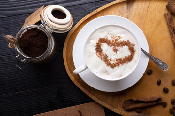 porcelain cup of coffee with ice cream and cinnamon heart served  at black wooden table. life style concept