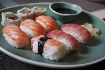 Japanese sushi food. Sushi set on green plate served with ginger and soy sauce. Sushi rolls, salmon nigiri, shrimp nigiri, tuna nigiri