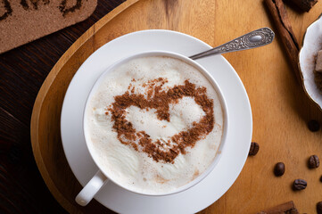 porcelain cup of coffee with ice cream and cinnamon heart served  at black wooden table. life style concept. flat lay