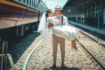 Wedding portrait of Asian couple at Bangkok train station, Asian groom carrying bride in wedding photography