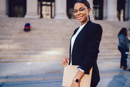 Portrait of Happy African American student of high financial university formal suit obtaining higher education in order to improve certification and career progression standing with folder in hands