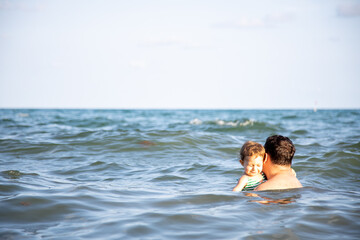 fatherly love concept. best dad. father hugs little cute toddler daughter in the water of the sea