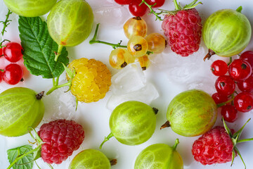 Fresh berries and pieces of ice on a white background close-up.
